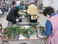 リースに植物で飾りをつけている